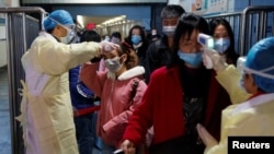 Medical workers take the temperature of passengers after they got off the train in Jiujiang, Jiangxi province, China, as the country is hit by an outbreak of a new coronavirus, January 29, 2020.