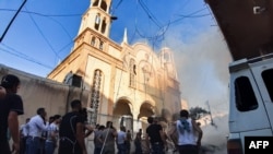 People gather at the scene of a car bomb explosion outside the Syriac Orthodox Church of the Virgin Mary in the predominantly Christian neighborhood of al-Wasti in the Kurdish-majority city of Qamishli in northeast Syria, July 11, 2019. 