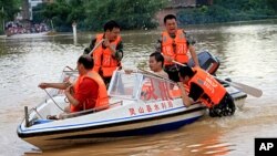 Chinese rescuers try to help residents cross a flooded street in Qinzhou, southwest China's Guangxi province on October 3, 2011.