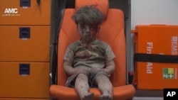 In this frame grab taken from video provided by the Syrian anti-government activist group Aleppo Media Center (AMC), a child sits in an ambulance after being pulled out or a building hit by an airstirke, in Aleppo, Syria, Aug. 17, 2016. 