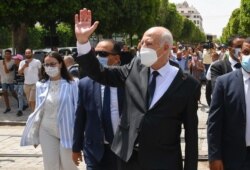 FILE - Tunisian President Kais Saied waves to bystanders as he strolls along the Avenue Habib Bourguiba in Tunis, Aug. 1, 2021.