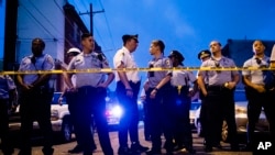 Para petugas kepolisian berkumpul dekat sebuah rumah saat menyelidiki penembakan di Philadelphia, 14 Agustus 2019. (AP Photo/Matt Rourke)