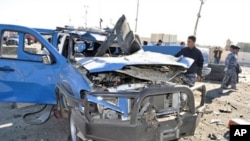 A policeman looks at a damaged police vehicle following a car bomb and minutes later a suicide bombing targeting the provincial headquarters in the western Iraqi city of Ramadi, 27 Dec, 2010.
