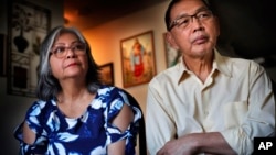 In this Dec. 1, 2017 photo, Poppy Sombah, left, and Freddy Sombah listen to an Indonesian community leader at their home in Somersworth, New Hampshire. The couple fled Indonesia to escape harassment from their Muslim neighbors following Poppy's conversion.