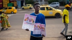 A young man sells calendars featuring Pope Francis outside the Cathedral Notre Dame du Congo in Kinshasa, Democratic Republic of the Congo, Jan. 29, 2023.