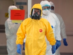FILE - Russian President Vladimir Putin, center, wearing a protective suit, enters a hall during his visit to the hospital for coronavirus patients in Kommunarka, outside Moscow, Russia, March 24, 2020.