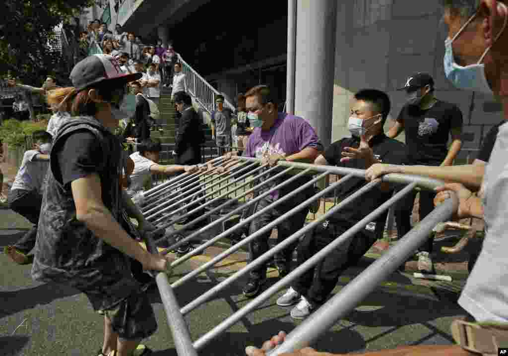 People wearing protective masks remove the metal barricades that protesters set up to block off main roads near the heart of the city's financial district, Hong Kong, Oct. 13, 2014. 