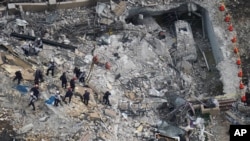 Rescue workers search in the rubble at the Champlain Towers South Condo, in Surfside, Fla, June 26, 2021.