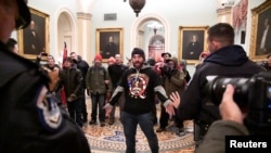 Trump supporter Douglas Austen Jensen, wearing a QAnon shirt, confronts police on the second floor of the U.S. Capitol after breaching security defenses, in Washington, January 6, 2021.