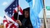 FILE - Zulfikar Mustafa puts up a U.S. flag during a rally in support of Uyghurs outside the State Department in Washington, Nov. 28, 2022. Uyghur Americans report an increase in transnational repression against them by China.