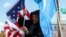 FILE - Zulfikar Mustafa puts up a U.S. flag during a rally in support of Uyghurs outside the State Department in Washington, Nov. 28, 2022. Uyghur Americans report an increase in transnational repression against them by China.