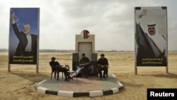 Các thành viên của lực lượng an ninh Hamas ngồi giữa các áp phích hình thủ lãnh nhóm Hamas Ismail Haniyeh (trái) và Quốc vương Qatar Emir Sheik Hamad bin Khalifa al-Thani tại Khan Younis, miền nam Dải Gaza