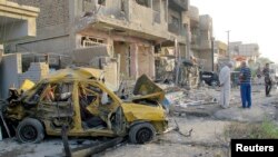 People inspect site of a car bomb attack in Baghdad, Iraq, Oct. 1, 2014.