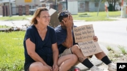 Homeless couple Angelique Hebert and husband Wilfred Hebert ask for help on a sidewalk as they try to recover from the effects of Hurricane Ida, Aug. 31, 2021, in Houma, La.