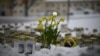 Lilin dan bunga diletakkan di atas salju di depan Sekolah Viertola untuk penghormatan kepada para korban di Vantaa, di utara ibu kota Finlandia, Helsinki, 3 April 2024. (Olivier MORIN / AFP)