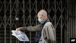 A man wearing a protective mask reads a Chinese language newspaper that says "Philippines bans travelers from China, Hong Kong and Macau" as he walks at Manila's Chinatown, Philippines, Feb. 3, 2020. 