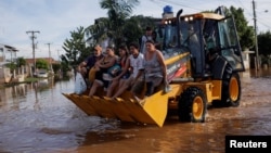 Evacuees ride in a loader after their homes were flooded at Eldorado do Sul, in Rio Grande do Sul Brazil May 7, 2024.