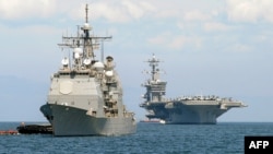 FILE - The cruiser USS Bunker Hill, left, and the U.S. aircraft carrier Carl Vinson sit anchored off Manila Bay after arriving on May 15, 2011.