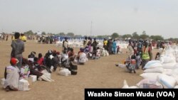 Displaced South Sudanese wait on Saturday, March 21, 2015, in Ganyiel, Unity state for sacks of food provided by the World Food Program (WFP) to be distributed. 
