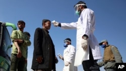 FILE - In this March 22, 2020 photo, health workers measure the temperature of Afghan passengers in an effort to prevent the spread of the coronavirus, as they enter Kabul trough Kabul's western entrance gate, in the Paghman district of Kabul.