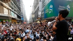 A protester speaks on a barricade as the anti-occupy Central demonstration protesters try to remove the barricade in the Mong Kok district of Hong Kong, Friday, Oct. 24, 2014. (AP Photo/Kin Cheung)