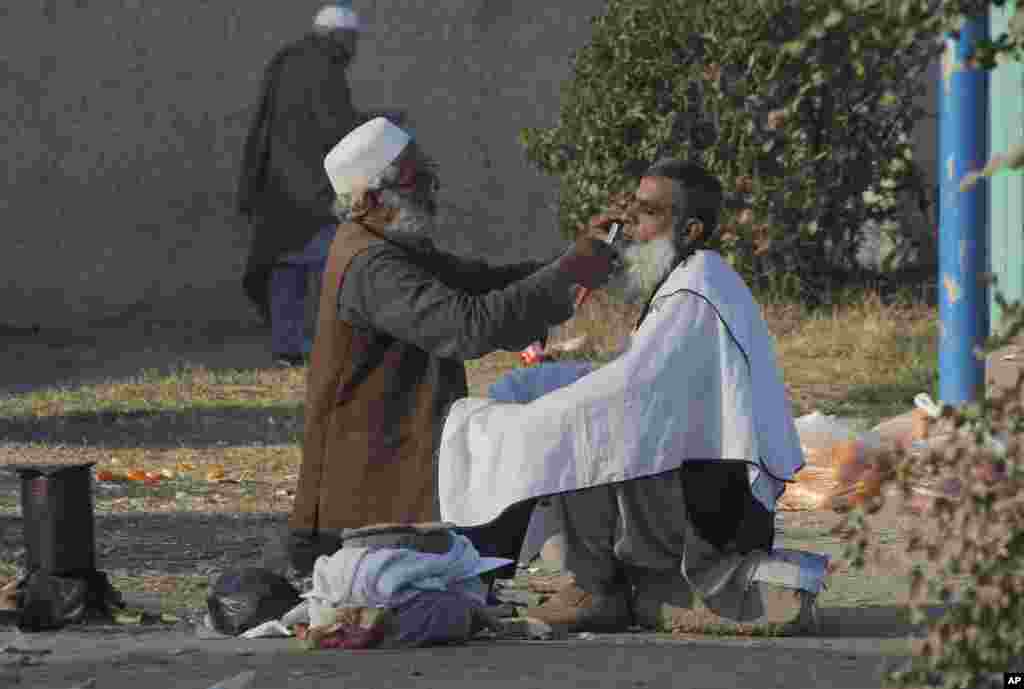 A Pakistani roadside barber attends to a customer in Peshawar, Pakistan.