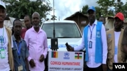 Humanitarian workers stand in front of convoy to transport CAR refugees back home, in Garoua Boulai, Cameroon, Oct. 23, 2019. (Moki Edwin Kindzeka/VOA)