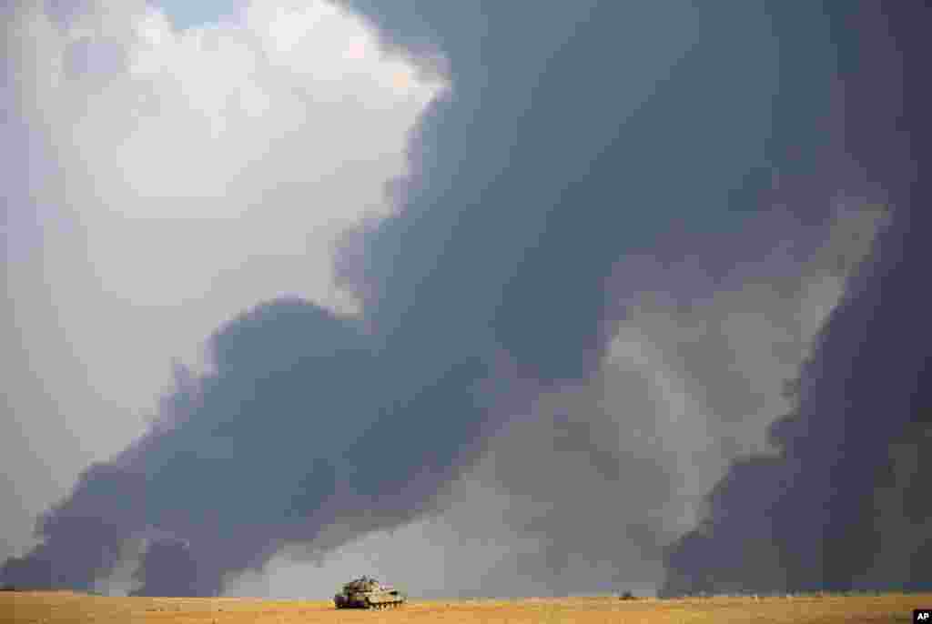 Israeli airstrikes pummel a wide range of targets in the Gaza Strip; an Israeli tank is seen here while heavy smoke rises from Gaza, July 22, 2014.&nbsp;