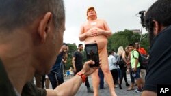 People take photos of a statue of a naked Republican presidential nominee Donald Trump in New York's Union Square, Aug. 18, 2016. City parks workers later removed the statue.