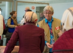 FILE - An official with Immigration, Refugees and Citizenship Canada, speaks with Syrian refugees waiting to pass through security at the beginning of a airlift to Canada, at the Beirut International airport, Dec. 10, 2015.