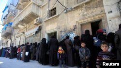 FILE - Women and children queue to receive free meals in Aleppo, Syria.