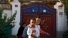 FILE - Uyghur children play while their relatives rest outside their house, which is decorated with Chinese lanterns and barbed wire, at the Unity New Village in Hotan, in western China's Xinjiang region, on Sept. 20, 2018. 