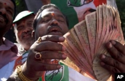 An activist of Congress party holds banned 500 and 1000 rupee notes during a protest against the government's decision to withdraw high denomination notes from circulation, in front of Reserve Bank of India. in Hyderabad, Nov. 28, 2016.