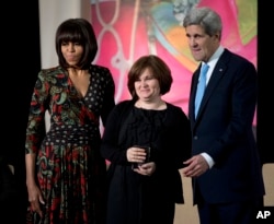 FILE - Then-First lady Michelle Obama, left, and Secretary of State John Kerry, right, honor Russian human rights activist, journalist Elena Milashina, with a Secretary of State’s International Women of Courage Award during a ceremony at the State Department in Washington.