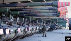 FILE - German soldiers walk beside tank howitzers 2000 prior to transportation to Lithuania at the Bundeswehr army base in Munster, northern Germany, Feb. 14, 2022.