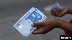 FILE - A person holds a new 1,000 naira note as the Central Bank of Nigeria releases the notes to the public through the banks in Abuja, Nigeria, Dec. 15, 2022.