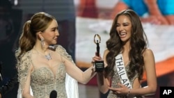 FILE - Anne Jakkaphong Jakrajutatip presents the ImpactWayv Challenge Award to Miss Thailand Anna Sueangam-iam during the final round of the 71st Miss Universe Beauty Pageant in New Orleans, Jan. 14, 2023.