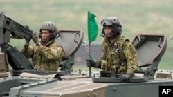 FILE - Japan's Ground Self-Defense Forces soldiers ride a self-propelled howitzer during an live fire exercise at training grounds in the East Fuji Maneuver Area in Gotemba, southwest of Tokyo, May 22, 2021.