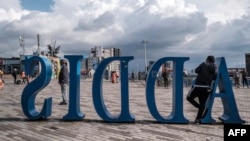 FILE - A man leans on a sign, in Addis Ababa, Sept. 26, 2022. Members of the tourism sector hope the November peace deal between the Ethiopian federal government and the Tigray People’s Liberation Front will help boost tourism. 