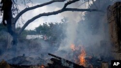 A local resident tries to stop the fire at a neighbor's house destroyed by a Russian attack in Mykolaiv, Ukraine, Aug. 5, 2022. 