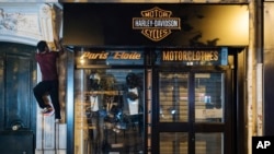 Kevin Ha from the collective 'On the Spot' climbs to turn off the lights of a store in Paris, July 29, 2022.