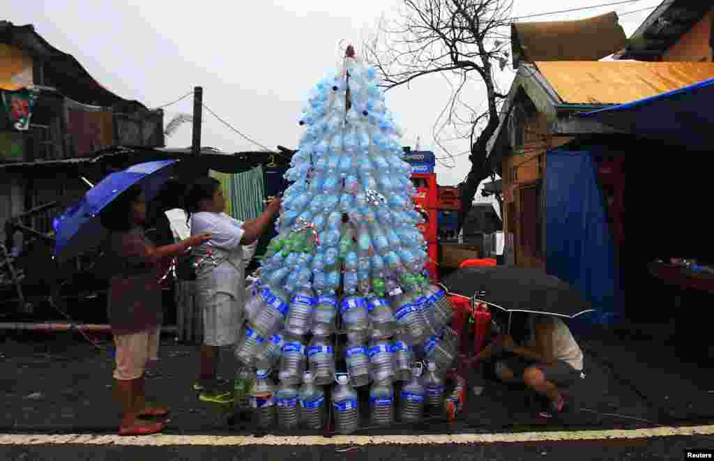 Para penyintas topan Haiyan membuat pohon Natal darurat dari botol dan kaleng kosong di wilayah Anibong, kota Tacloban, Filipina tengah (24/12).