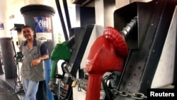 Un ciudadano observa un surtidor de gasolina encadenado debido a la falte de combustible en Caracas.