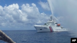 FILE - In this Sept. 23, 2015, file photo, Chinese Coast Guard members approach Filipino fishermen as they confront each other off Scarborough Shoal in the South China Sea, also called the West Philippine Sea. (AP Photo/Renato Etac, File)