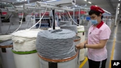 A worker watches as a machine processes cotton yarn at a Huafu Fashion plant, as seen during a government organized trip for foreign journalists, in Aksu in western China's Xinjiang Uyghur Autonomous Region, April 20, 2021.