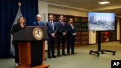 A screen shows a photo of Lafarge's cement plant in Jalabiyeh, Syria, as the deputy Attorney General of the United States Lisa Monaco, left, speaks during a press conference at the U.S. Attorney's Office in New York, Oct. 18, 2022.