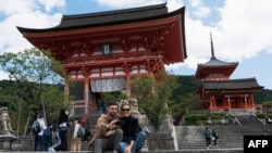 Wisatawan berfoto selfie di dekat pintu masuk kuil Kiyomizu-dera di Kyoto pada 11 Oktober 2022. (Fred MERY / AFP)