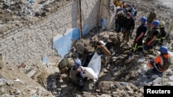 Ukrainian army soldiers and fire fighter extract the body of an army officer, who was found among the remains of the building beside the TV tower, in the recently liberated town of Izium, Kharkiv region, Sept. 29, 2022. 