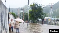 La gente camina por una calle inundada en Maracay, Venezuela, el 6 de octubre de 2022. La imagen es una captura de pantalla obtenida de un video de las redes sociales. [Foto: Carmen Elisa Pecorelli/vía Reuters]