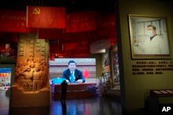Chinese President Xi Jinping is seen on screen and poster at an exhibition highlighting China's fight against the COVID-19 pandemic at the Museum of the Community Party of China in Beijing, Wednesday, Oct. 12, 2022.